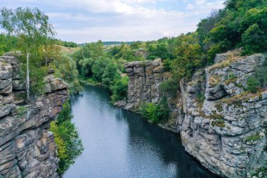 Aralarından bir ırmak geçen arge taşları ve berrak su. Ağaçlar kayalarda yetişir..