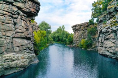 Aralarından bir ırmak geçen büyük kayalar ve berrak su. Ağaçlar kayalarda yetişir..