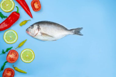 Dorado balığı ve sebze: salatalık, domates, biber, limon mavi arka planda bulunur. Mutfak için arkaplan dokusu
