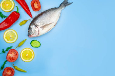 Dorado balığı ve sebze: salatalık, domates, biber, limon mavi arka planda bulunur. Mutfak için arkaplan dokusu