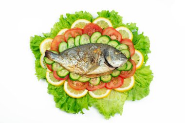 Sebzeli ızgara dorado balığı: salata, domates, salatalık, yeşil biber ve beyaz arka planda limon.