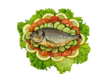 Sebzeli ızgara dorado balığı: salata, domates, salatalık, yeşil biber ve beyaz arka planda limon.