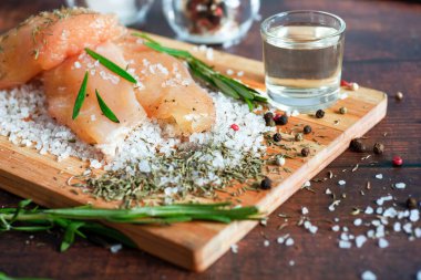 Kurutulmuş tavuk, üzerinde baharat ve deniz tuzu olan bir tahtada yatıyor. Biberiye, kakule, biber..