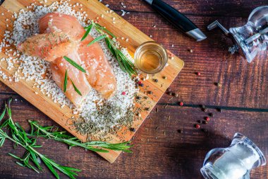 Kurutulmuş tavuk, üzerinde baharat ve deniz tuzu olan bir tahtada yatıyor. Biberiye, kakule, biber..