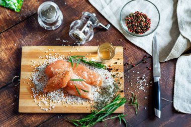 Kurutulmuş tavuk, üzerinde baharat ve deniz tuzu olan bir tahtada yatıyor. Biberiye, kakule, biber..