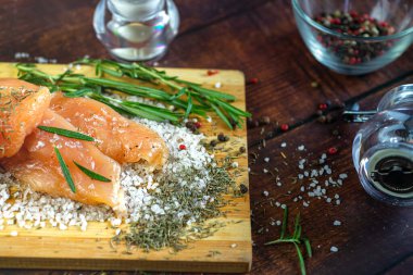 Kurutulmuş tavuk, üzerinde baharat ve deniz tuzu olan bir tahtada yatıyor. Biberiye, kakule, biber..