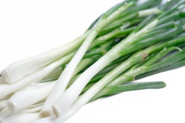 Beyaz arka planda yeşil tüylü taze soğanlar.