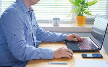 Genç adam evdeki bilgisayarda çalışıyor.