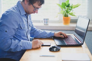 Genç adam evdeki bilgisayarda çalışıyor.