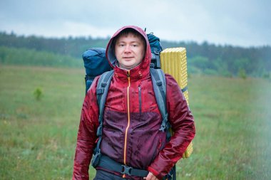 Dağlarda gezerken yağmurda ıslanan büyük bir sırt çantalı bir yürüyüşçü.