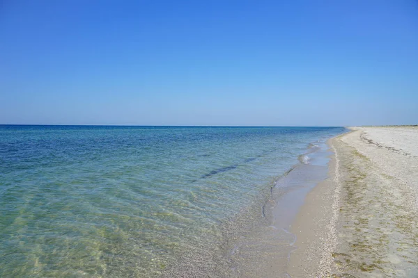 Beyaz bir kum adasının açıklarında berrak suları olan masmavi bir deniz.