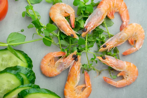 Karides ve yeşiller taş bir tezgahın üzerinde yatıyor.