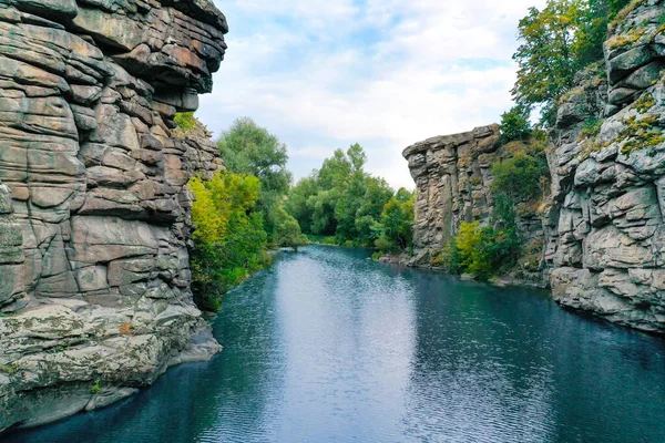 Aralarından bir ırmak geçen büyük kayalar ve berrak su. Ağaçlar kayalarda yetişir..
