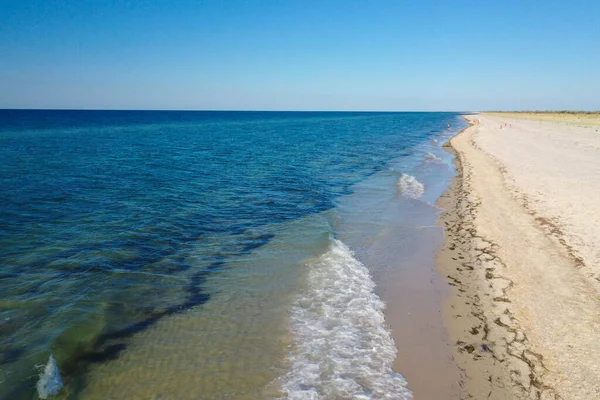 Adanın kıyısındaki dalgalardan gelen mavi su ve beyaz köpük. en üstteki görünüm