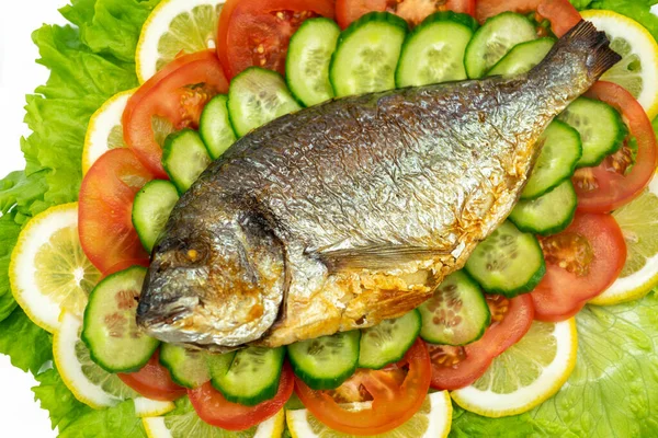 Sebzeli ızgara dorado balığı: salata, domates, salatalık, yeşil biber ve beyaz arka planda limon.
