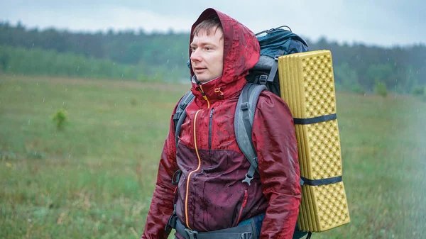 Dağlarda gezerken yağmurda ıslanan büyük bir sırt çantalı bir yürüyüşçü.