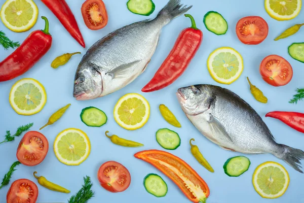 Dorado balığı ve sebze: salatalık, domates, biber, limon mavi arka planda bulunur. Mutfak için arkaplan dokusu