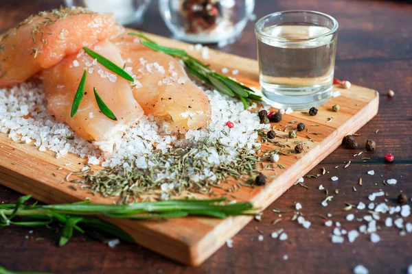 Kurutulmuş tavuk, üzerinde baharat ve deniz tuzu olan bir tahtada yatıyor. Biberiye, kakule, biber..