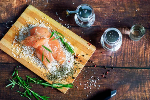 Kurutulmuş tavuk, üzerinde baharat ve deniz tuzu olan bir tahtada yatıyor. Biberiye, kakule, biber..