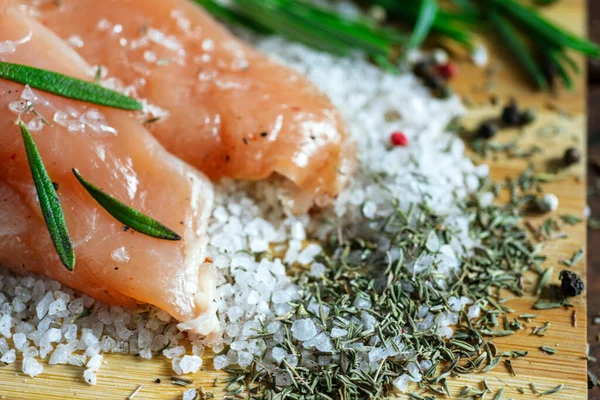 Kurutulmuş tavuk, üzerinde baharat ve deniz tuzu olan bir tahtada yatıyor. Biberiye, kakule, biber..