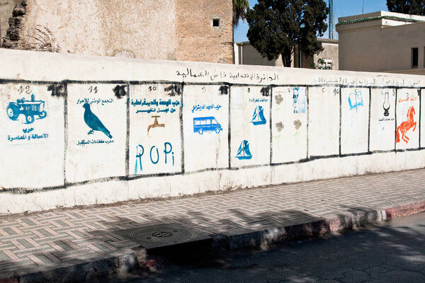 Traditional pre-election political campaign layout with colorful parties symbolic logos stamped on the wall, Fes, Morocco