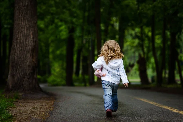 Blond meisje loopt weg naar donker park alleen — Stockfoto