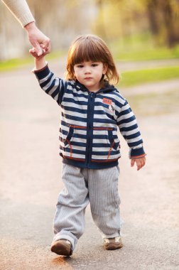 Küçük çocuk annesinin elini tutarak bahar günü yürüyüş