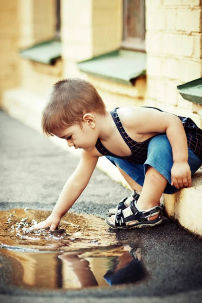 Bonito menino lavando as mãos na poça — Fotografia de Stock