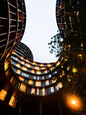 A view towards the dark evening sky from inner garden space of round Axel Towers, example of new Danish architecture in the centre of Copenhagen, comprising space for living, work, recreation, entertainment clipart