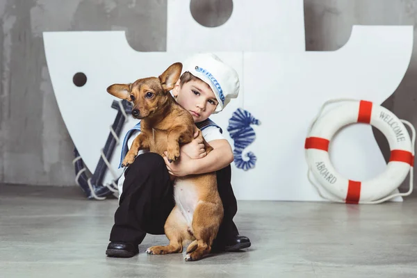 Мальчик-каюта с маленькой собачкой перед кораблем — стоковое фото