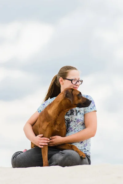 Flicka bär glasögon omfamna och kyssa sin hund — Stockfoto
