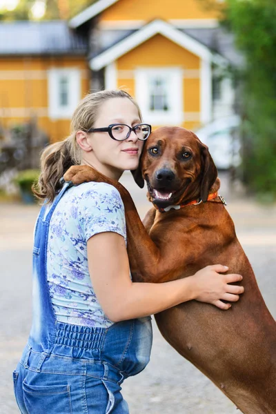 Zwanger meisje dragen bril omarmen en zoenen hond — Stockfoto