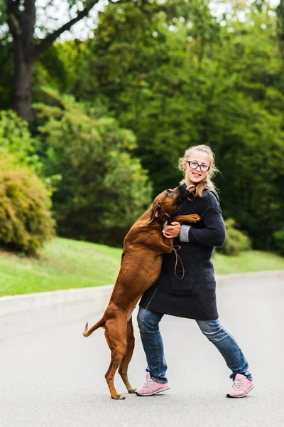 Menina feliz brincando com seu cão alegre, pulando, dançando — Fotografia de Stock