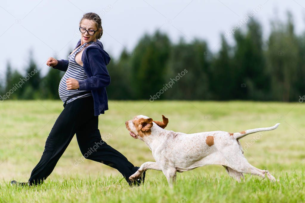 pregnant girl running at nature with dog friend