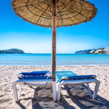 Mavi gökyüzüne karşı güneş şemsiyeli plaj sandalyeleri