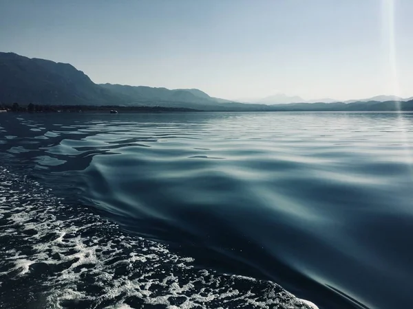 Ondas en la estela de un barco pontón al amanecer en un lago en Turquía —  Fotos de Stock