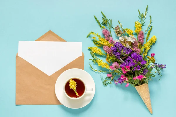 Flores de campo, envelope de artesanato e xícara de chá de ervas — Fotografia de Stock