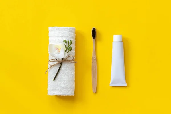 Brosse en bambou écologique naturelle, serviette blanche et tube de dentifrice. Set pour le lavage sur papier fond jaune. Espace de copie pour le texte ou votre conception Vue de dessus Pose plate — Photo