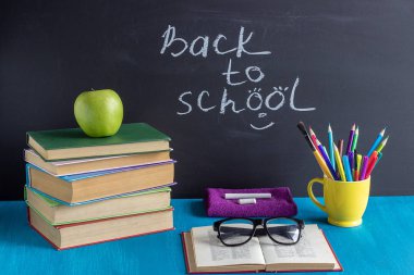 Okula ve öğrencilerin işyerine metin geri. Kitap kırtasiye gözlük arka plan siyah tebeşir Kavramı Eğitim mavi masada elma tebeşir