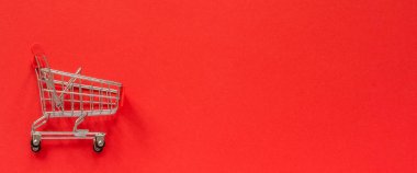Kırmızı arka planda küçük boş alışveriş arabası sepeti. Konsept satışı. Üst görünüm Kopyala alanı