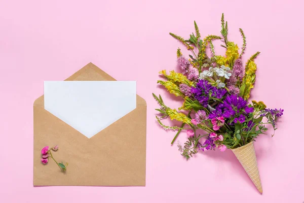 Букет квітів у вафельному конусі та ремісничій конверті з паперовою карткою — стокове фото