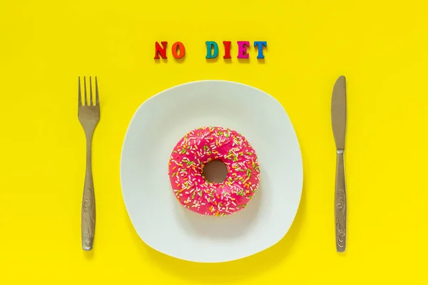 No diet and Pink donut on white plate and knife fork on yellow background.