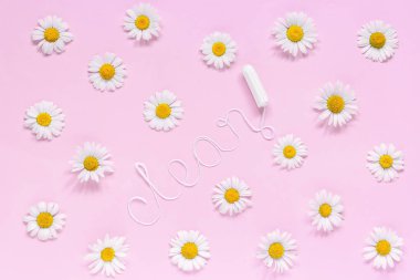 Beyaz iplikten temizlenmiş hijyenik kadın tamponu ve pembe arka planda papatyalar.