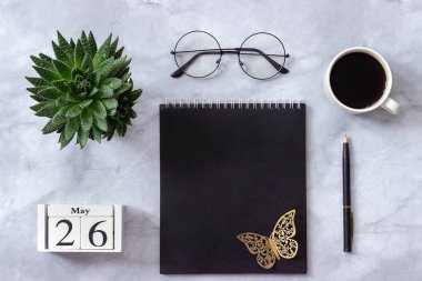 Ofis veya ev masası. Ahşap küpler takvim 26 Mayıs. Siyah not defteri, kahve fincanı, sulu, mermer arka plan üzerinde gözlük Konsept şık işyeri Düz yatıyordu Üst görünüm