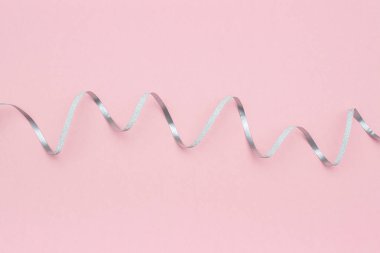 En az tarzda pembe arka plan üzerinde parlak gümüş kurdele flamanları serpantin. Kutlama, parti, tatil için konsept süslemeler