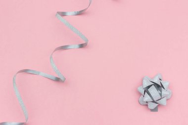 Gümüş flamalar serpantin ve en az tarzda pembe arka plan üzerinde yay. Kutlama, parti, tatil, Noel, doğum günü, metin veya tasarım için yeni yıl Şablonu için konsept süslemeleri. Kopyalama alanı