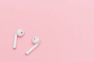 Pembe kağıt arka planda beyaz kablosuz kulaklık. Metin ya da tasarımın için şablon. Düz konum Üst Görünüm Kopyalama alanı