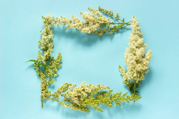 Σύνθεση λουλουδιών. Frame φύση floral ορθογώνιο στεφάνι του ανθισμένη κλαδί λευκά λουλούδια σε μπλε φόντο. Επίπεδη θέα πάνω. Αναπαράσταση προτύπου για καρτ ποστάλ, κείμενο γραμμάτων ή το σχέδιό σας — Φωτογραφία Αρχείου