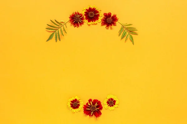 Flower composition. Frame floral round wreath of yellow red flowers on orange background. Flat lay Top-down composition. Copy space Mock up Template for postcard, lettering text or your design