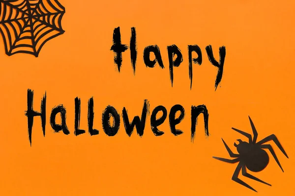 Halloween background. Text Happy Halloween Black paper spider and spiderweb on orange background